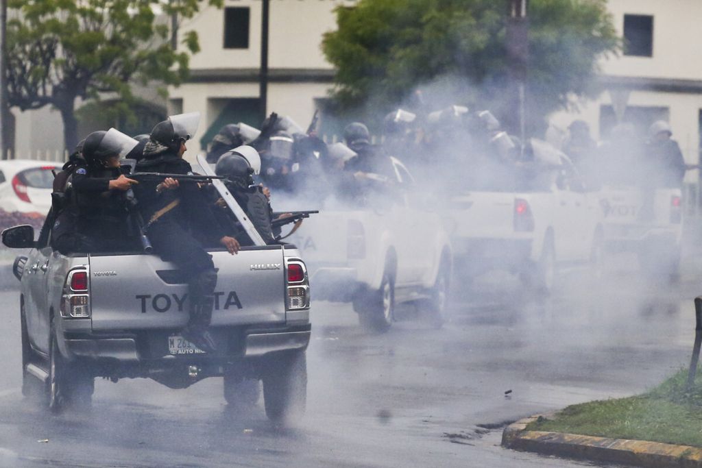 Dalam foto 28 Mei 2018 ini, polisi dengan perlengkapan antihuru-hara yang mengendarai bagian belakang truk pikap menembakkan senapan mereka ke arah mahasiswa yang memprotes Presiden Nikaragua Daniel Ortega di Managua. Lebih dari 300 orang tewas dalam kekerasan sejak pertengahan April.