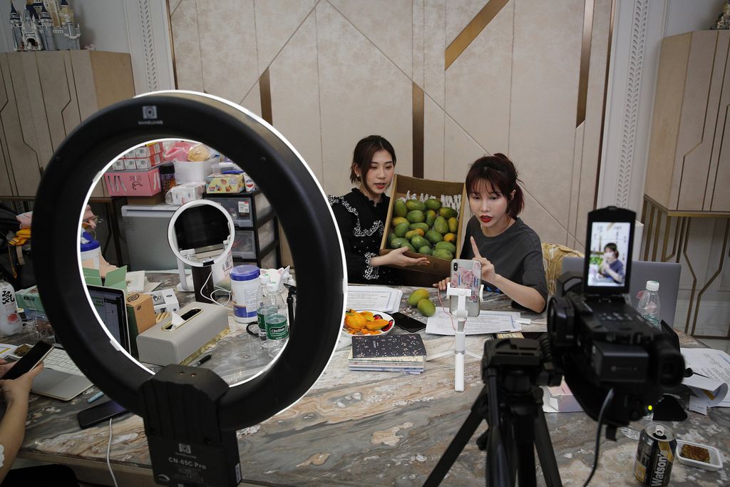 Dalam foto 5 Mei 2020 ini, selebritas daring China, Zhang Mofan (kanan), memperkenalkan mangga segar kepada klien dan penggemarnya melalui <i>live streaming </i>di rumahnya di Beijing, China. 