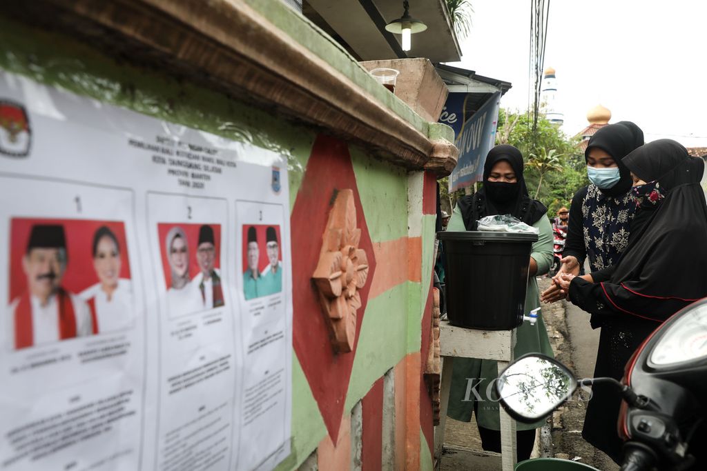 Calon pemilih mencuci tangan sebelum masuk TPS 15 Kelurahan Pamulang Timur, Kecamatan Pamulang, Kota Tangerang Selatan, Banten, untuk mengikuti pemilu suara ulang, Minggu (13/12/2020).