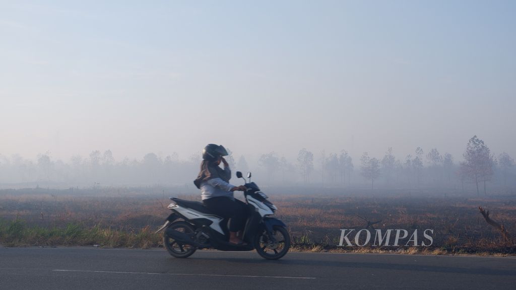 Warga menembus kabut asap pekat di Jalan Trikora, Kota Banjarbaru, Kalimantan Selatan, Minggu (1/10/2023) pagi.