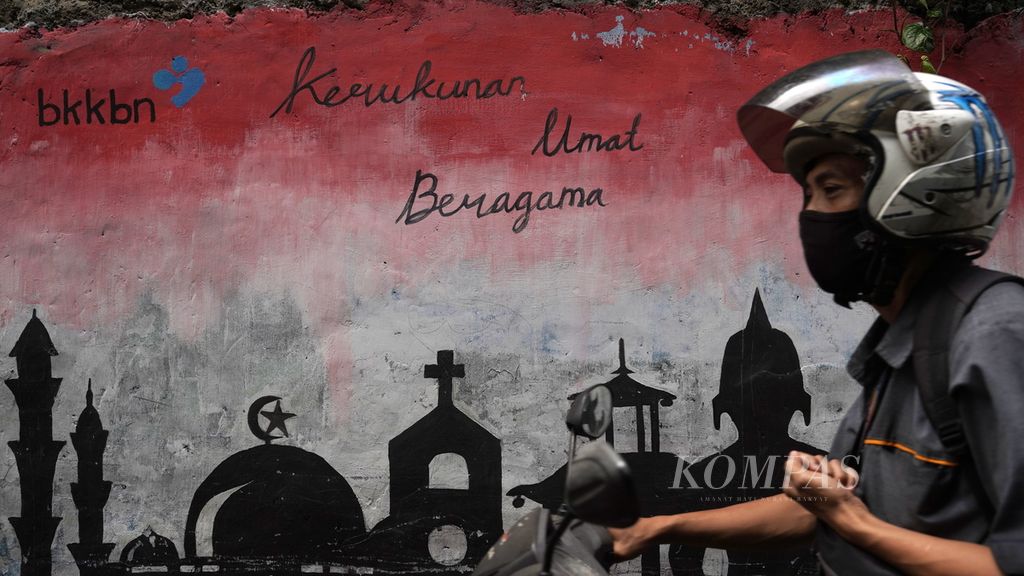 Warga melintasi mural kerukunan umat beragama di Kampung KB, Bintara Jaya, Kota Bekasi, Jawa Barat, Senin (13/2/2023).