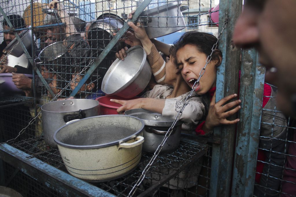 Warga Palestina berdesakan untuk memperoleh jatah makanan gratis di kamp pengungsi Jabaliya di Jalur Gaza, Senin (18/3/2024). 