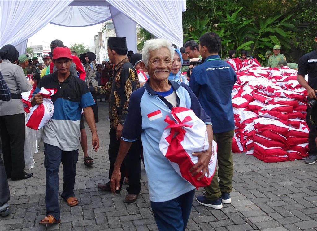 A resident smiles happily after receiving a package of presidential aid staples at the parking lot of the Graha Saba building, Solo, Central Java, Wednesday (5/6/2019).