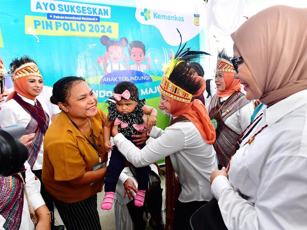 Nyonya Wury Ma’ruf Amin menggendong seorang anak yang akan mendapatkan vaksin polio di Posyandu Rajawali 3, kompleks Graha Nendali, Jalan Raya Sentani-Waena, Nendali, Kecamatan Sentani Timur, Kabupaten Jayapura, Selasa (23/7/2024).