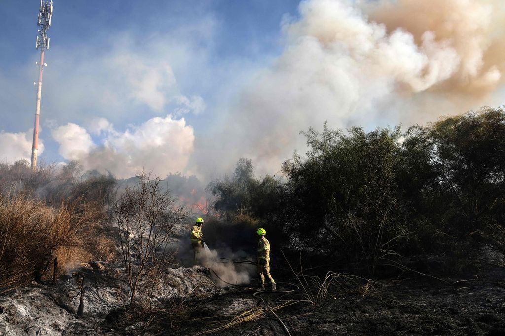 Petugas berupaya memadamkan api di area terbuka di Lod, dekat Tel Aviv, Israel, yang dihantam rudal dari Yaman, Minggu (15/9/2024).  