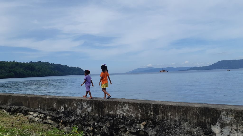 Dua bocah berjalan di atas talud di pesisir Desa Haruku, Pulau Haruku, Kabupaten Maluku Tengah, Maluku, Selasa (10/11/2020).