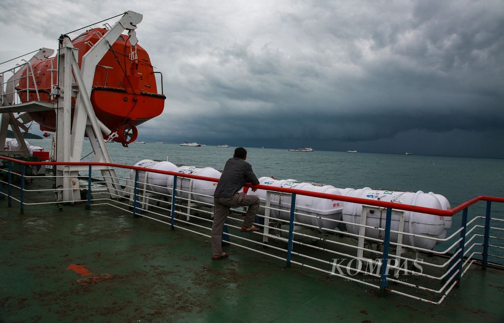 Penumpang feri penyeberangan menuju Pelabuhan Merak, Cilegon, Banten, menyaksikan perairan Selat Sunda yang dinaungi awan gelap, Rabu (28/12/2022). 