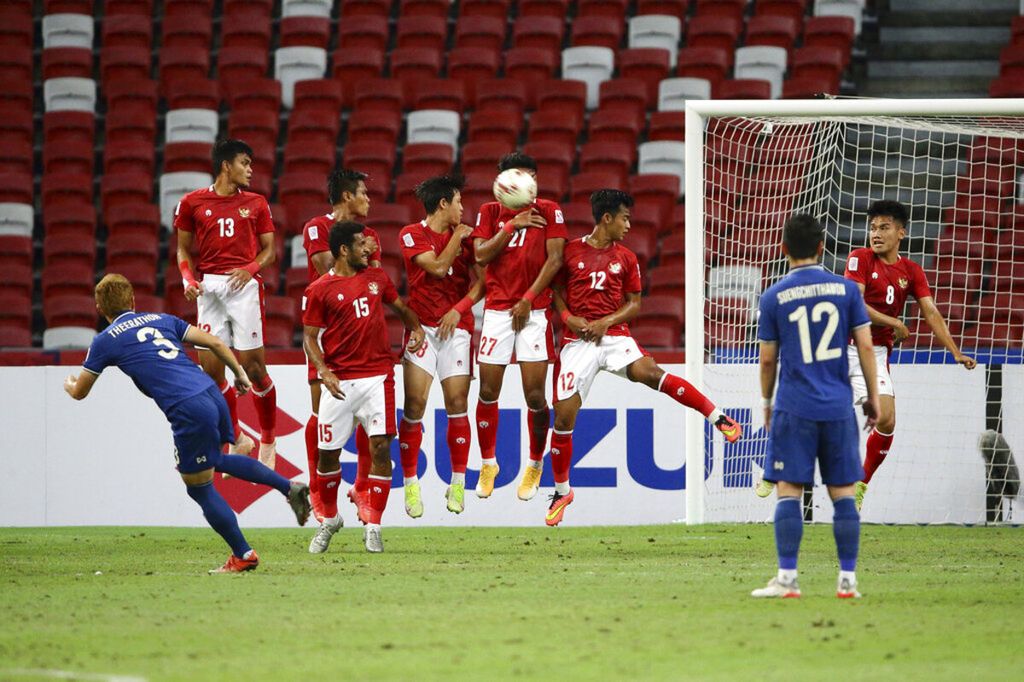 Sejumlah pemain Indonesia melompat untuk menahan tendangan bebas yang dilakukan pemain Thailand, Theerathon Bunmathan, dalam laga kedua final Piala AFF yang digelar di Stadion Nasional Singapura, Sabtu (1/1/2022). Indonesia tampil lebih dominan pada babak pertama dan berhasil unggul pada menit ketujuh.