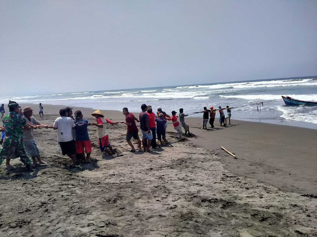 Warga dan Tim SAR Gabungan menarik kapal nelayan yang terbalik di Pantai Wagir Indah, Adipala, Cilacap, Jawa Tengah, Rabu (18/10/2023).