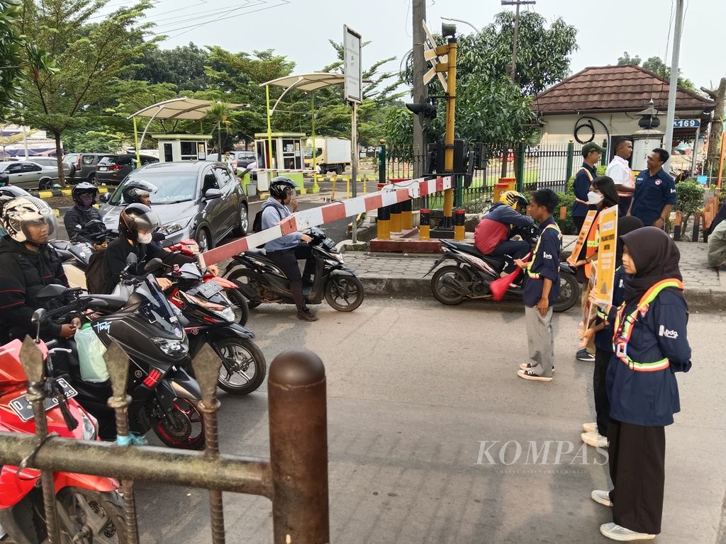 Anggota Komunitas Edan Sepur Bandung berdiri di depan pintu pelintasan kereta api Stasiun Kiaracondong, Kota Bandung, Jawa Barat, Jumat (22/3/2024). Aksi ini dilakukan saat kereta melewati pelintasan tersebut.