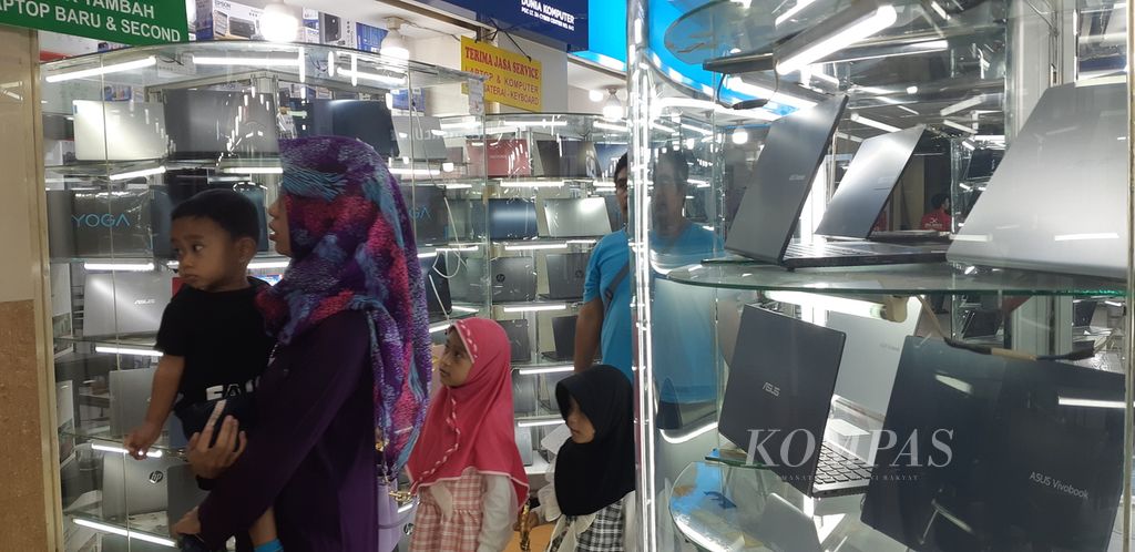 Sekelompok keluarga melintas di antara toko penjualan komputer jinjing di Pusat Grosir Cililitan, Jakarta Timur, Sabtu (28/10/2023).