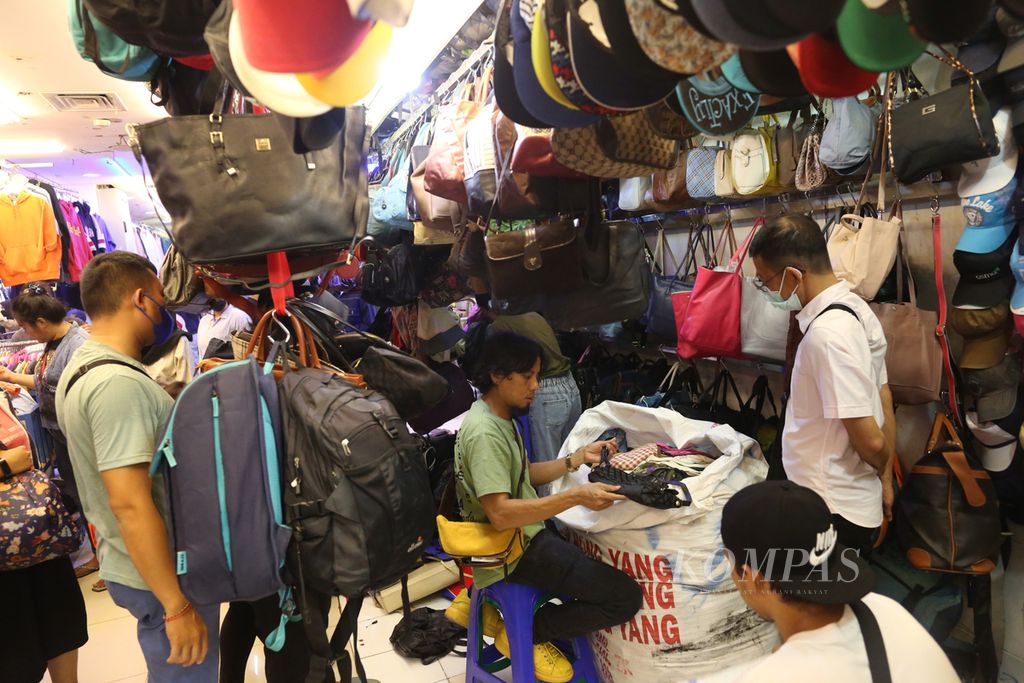 Pedagang memilih tas bekas impor yang baru dibuka dari karung di Pasar Senen Blok 3, Jakarta Pusat, Minggu (29/5/2022). Berbelanja barang bekas impor, baik tas, sepatu, maupun pakaian, kini populer di tengah masyarakat karena harganya jauh lebih murah.