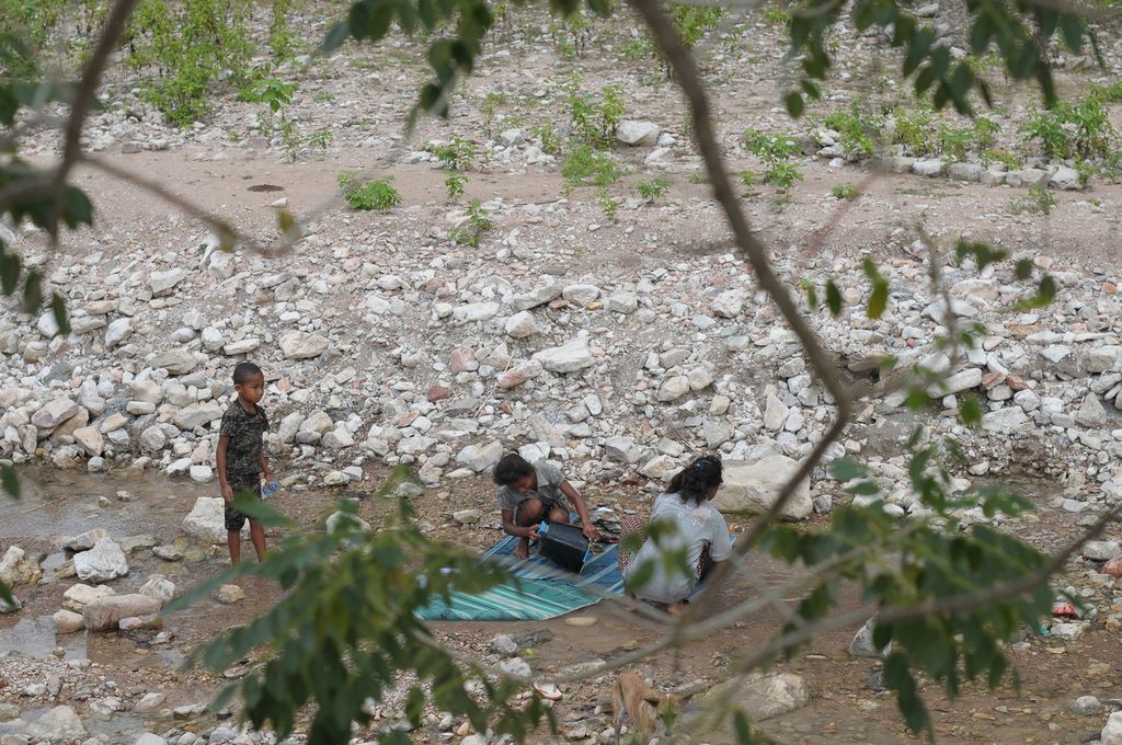 Esra Notunis (14) bersama dua adiknya, Ferni (12) dan Miki Nitboho (7), mencuci tikar dan pakaian di Sungai Noefatu, Desa Falas, Kecamatan Kie, Kabupaten Timor Tengah Selatan, Nusa Tenggara Timur, Senin (30/5/2022).