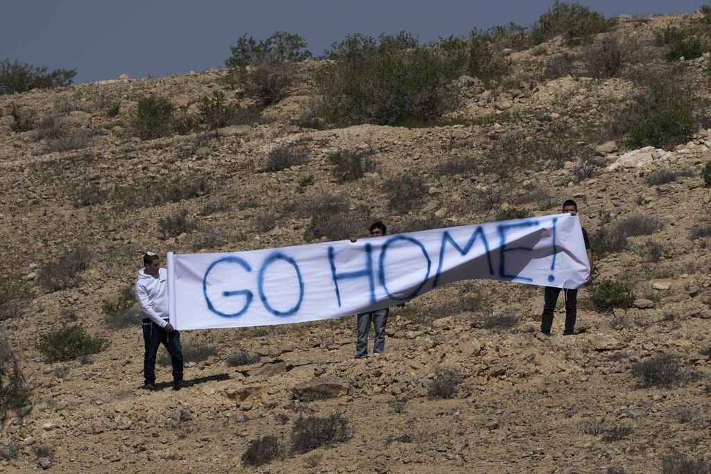 Sejumlah aktivis Israel mengangkat spanduk berisi tulisan "pulang". Mereka berunjuk rasa menolak Pertemuan Tingkat Tinggi Negev yang digelar di Sde Boker pada Senini (28/3/2022).