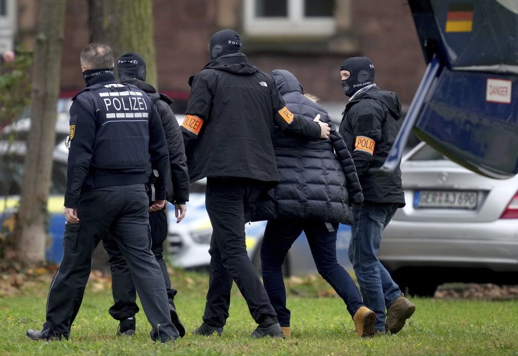 Seorang tersangka anggota kelompok ekstremis sayap kanan (kedua dari kanan) dibawa dari sebuah helikopter polisi setelah tiba untuk interogasi di kantor jaksa penuntut umum di Karlsruhe, Jerman, 7 Desember 2022. Ribuan polisi dikerahkan dalam operasi besar-besaran menangkap anggota kelompok tersebut. 