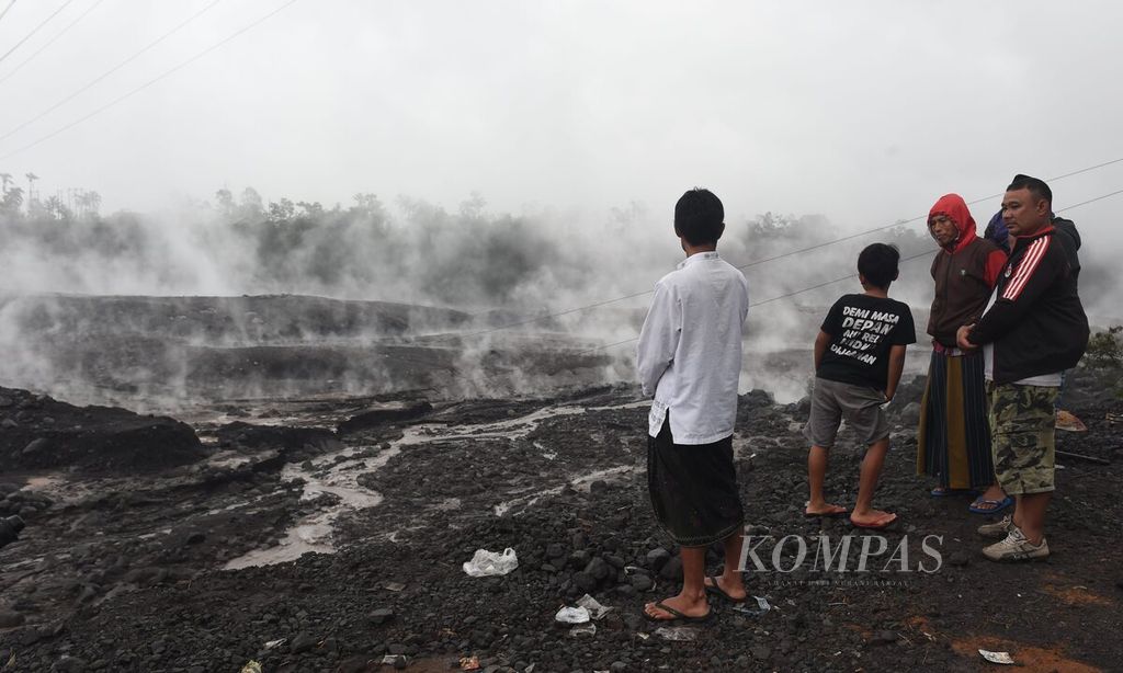 Warga Residents see the condition of Besuk Kobokan filled with volcanic material that issued smoke after the eruption of Mount Semeru, Supituku Village, Pronojiwo District, Lumajang Regency, East Java, Sunday (4/12/2022).