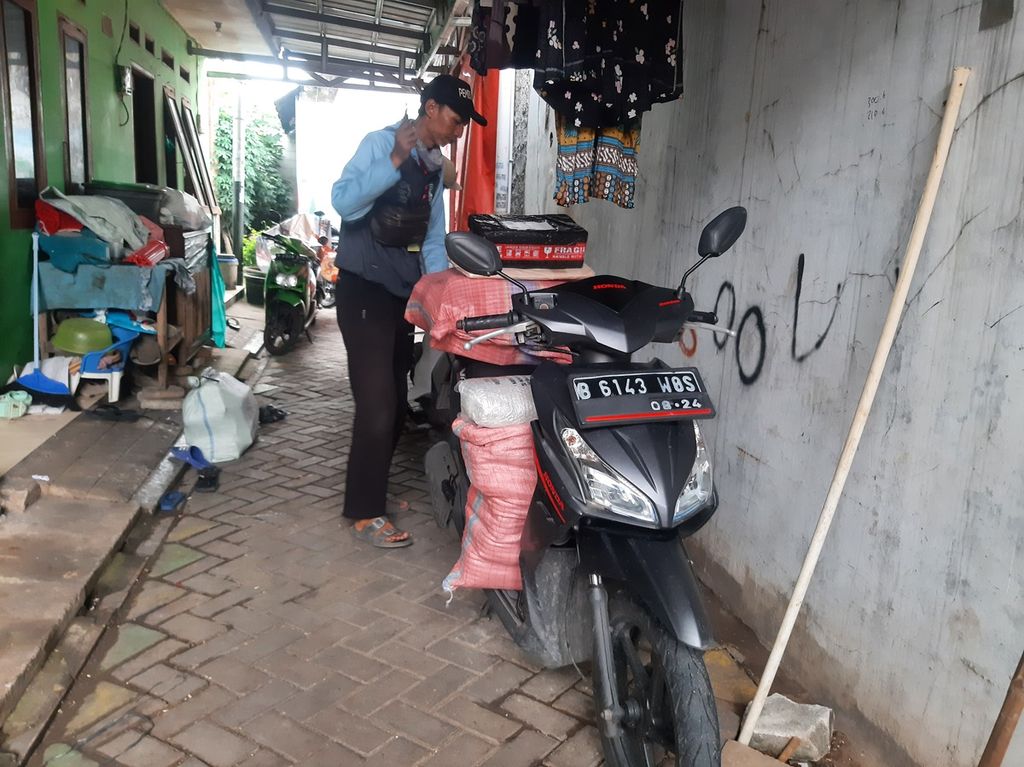 Seorang kurir ekspedisi menyiapkan motornya untuk mengantarkan barang di kawasan Larangan, Kota Tangerang, Banten, Kamis (9/3/2023).