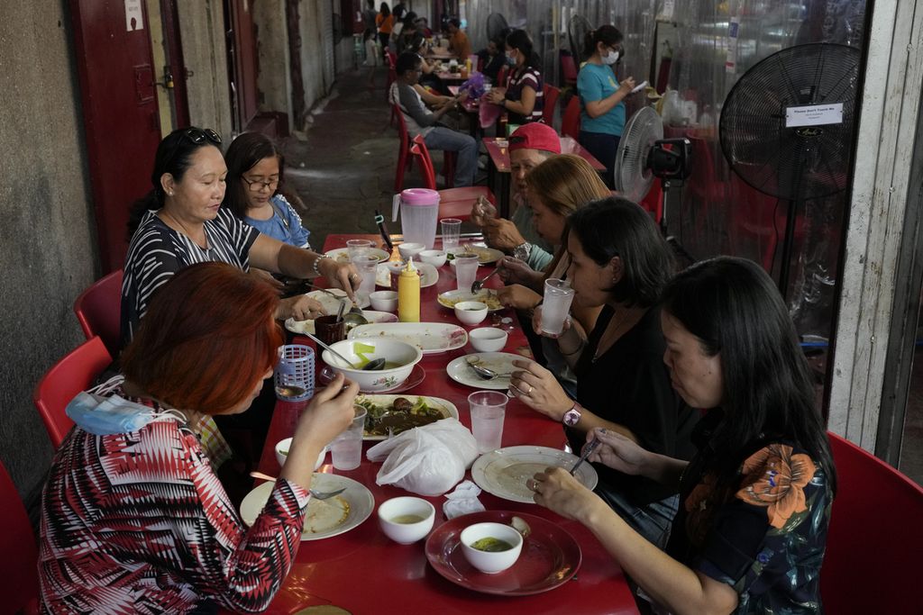 Pengunjung restoran menikmati hidangan di meja tanpa ada sekat plastik yang sebelumnya ditempatkan seiring pelonggaran pembatasan sosial di Manila, 1 Maret 2022. 