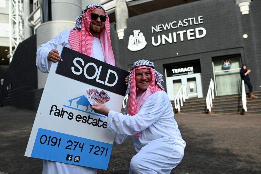 Suporter tim Liga Inggris, Newcastle United, mengenakan busana Timur Tengah berpose dengan papan bertuliskan Dijual di depan Stadion St James Park, Newcastle, 8 Oktober 2021. Konsorsium yang dipimpin Arab Saudi telah menjadi pemilik baru Newcastle United sejak 7 Oktober 2021.