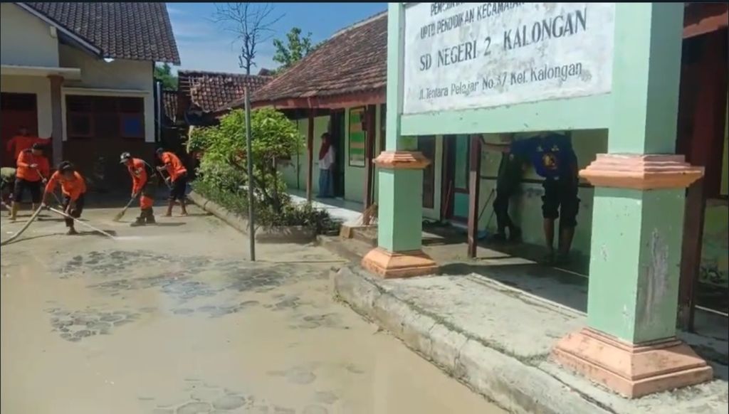 Personel Badan Penanggulangan Bencana Daerah Grobogan bersama sukarelawan bekerja bakti membersihkan lumpur sisa banjir di SDN 2 Kalongan, Grobogan, Jawa Tengah, Jumat (9/2/2024).
