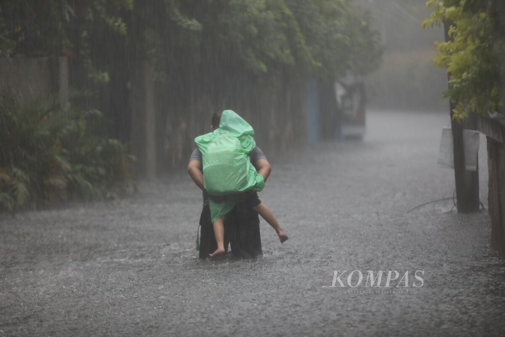 Seorang warga menggendong anak menembus banjir di kawasan Karet Kuningan, Jakarta, Selasa (4/10/2022). Berdasarkan data dari Badan Meteorologi, Klimatologi, dan Geofisika (BMKG), Badan Penanggulangan Bencana Daerah (BPBD) DKI Jakarta memberi peringatan terkait adanya cuaca ekstrem di Jakarta pada 2-8 Oktober 2022. 