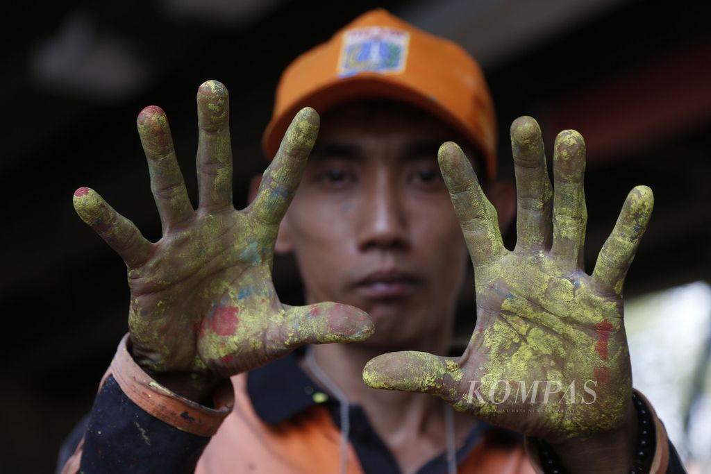 Petugas penanganan prasarana dan sarana umum memperlihatkan tangan yang penuh cat di kolong Jalan Layang Tebet, Jakarta Selatan, Selasa (17/10/2023).