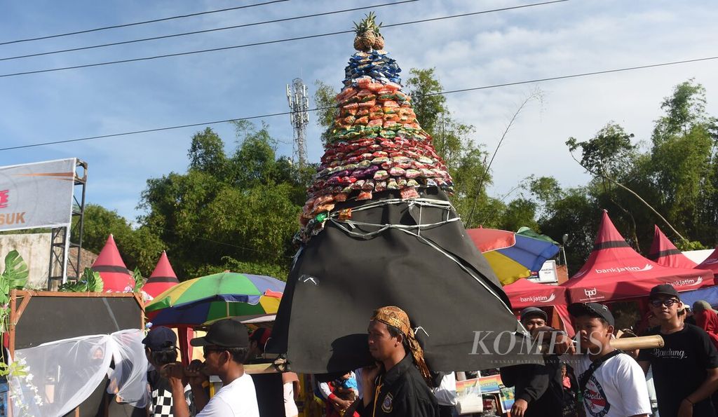 Peserta pawai bersih desa membawa gunungan berisi makanan ringan di Desa Medali, Kecamatan Puri, Kabupaten Mojokerto, Jawa Timur, Minggu (19/3/2023). Selain sebagai bentuk syukur dan berharap kehidupan akan terus baik, bersih desa juga untuk menjaga silaturahmi antarwarga. Pawai desa itu diikuti oleh semua RT di Desa Medali. Banyak dari peserta mengusung tema agraris. 