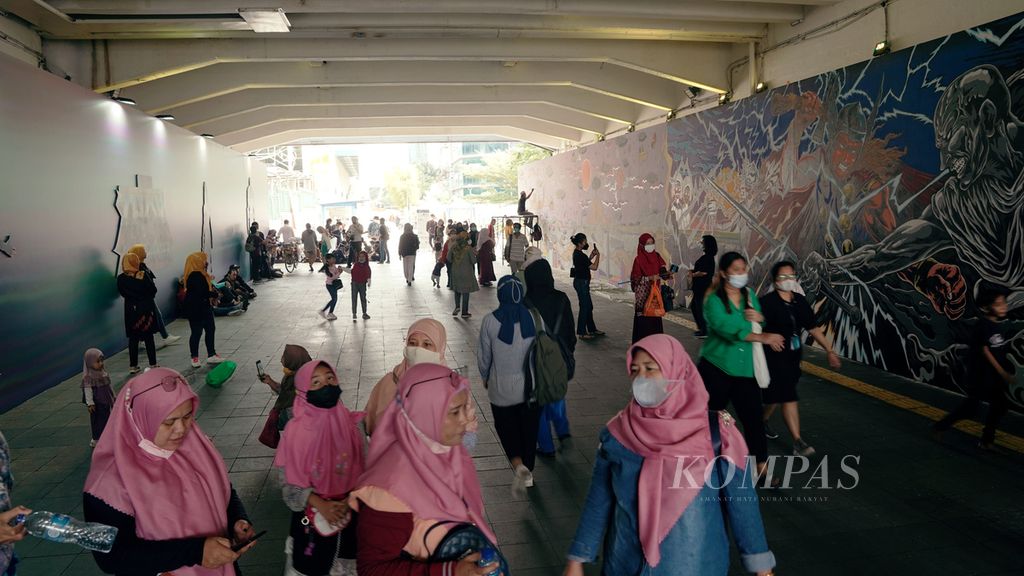 Warga melintasi mural kolaborasi di Terowongan Kendal, Kawasan TOD Dukuh Atas, Jakarta Pusat, Selasa (5/7/2022). Pameran instalasi mural kolaborasi JXB, MRT Jakarta, dan Disney Marvel Indonesia tersebut berlangsung hingga 15 Juli. 