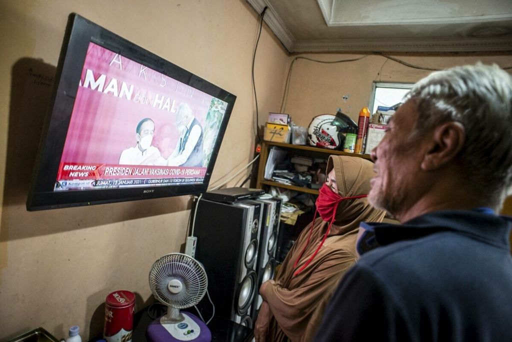 Warga menonton televisi yang menayangkan langsung penyuntikan vaksin CoronaVac perdana di Jakarta, Rabu (13/1/2021). Presiden Joko Widodo menjadi orang pertama di Indonesia yang disuntik vaksin Covid-19 buatan perusahaan farmasi Sinovac asal China seusai BPOM mengeluarkan izin pengunaan darurat vaksin. 
