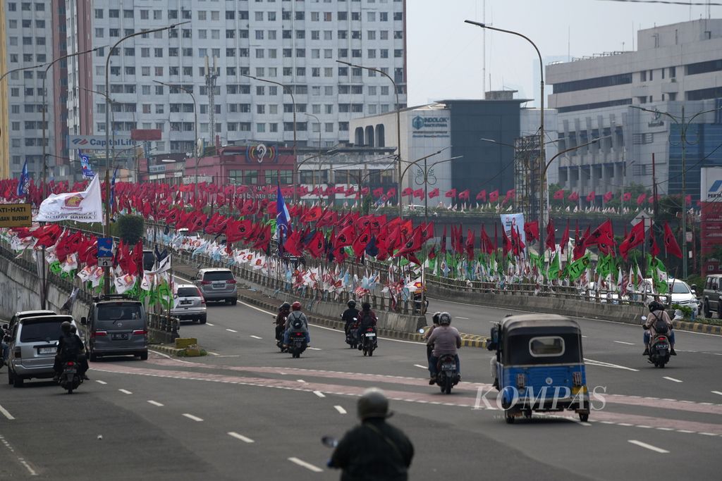 Pengendara melintasi bendera partai politik peserta Pemilu 2024 yang dipasang di Jalan Pramuka, Jakarta Timur, Senin (1/1/2024). Masa kampanye digunakan partai politik untuk memasang alat peraga kampanye. 