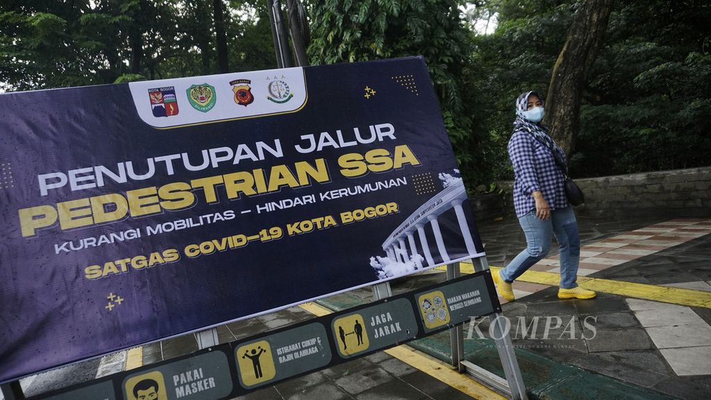 Warga melintasi papan penutupan jalur pedestrian di kawasan sistem satu arah (SSA) Kota Bogor, Jawa Barat, bagi aktivitas umum, Minggu (6/2/2022). 
