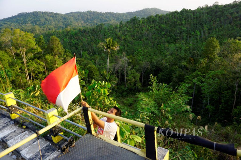 Saiful (25), sedang membenarkan posisi bendera di mobil truknya di Jalan Samboja-Sepaku, Kecamatan Samboja, Kabupaten Kutai Kartanegara, Senin (26/8/2019). Lokasi itu merupakan perbatasan Penajam Paser Utara dan Kutai Kartanegara yang akan menjadi lokasi ibu kota baru.