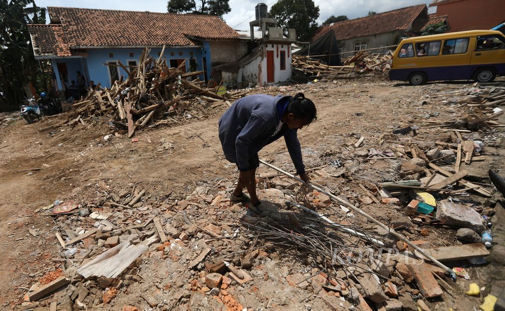Pemulung mengumpulkan besi bekas, pipa bekas, kabel, dan potongan baja ringan saat ekskavator membersihkan puing bangunan rumah warga di lokasi gempa di Kampung Wargaluyu, Desa Nagrak, Kecamatan Cianjur, Kabupaten Cianjur, Jawa Barat, Minggu (4/12/2022). 