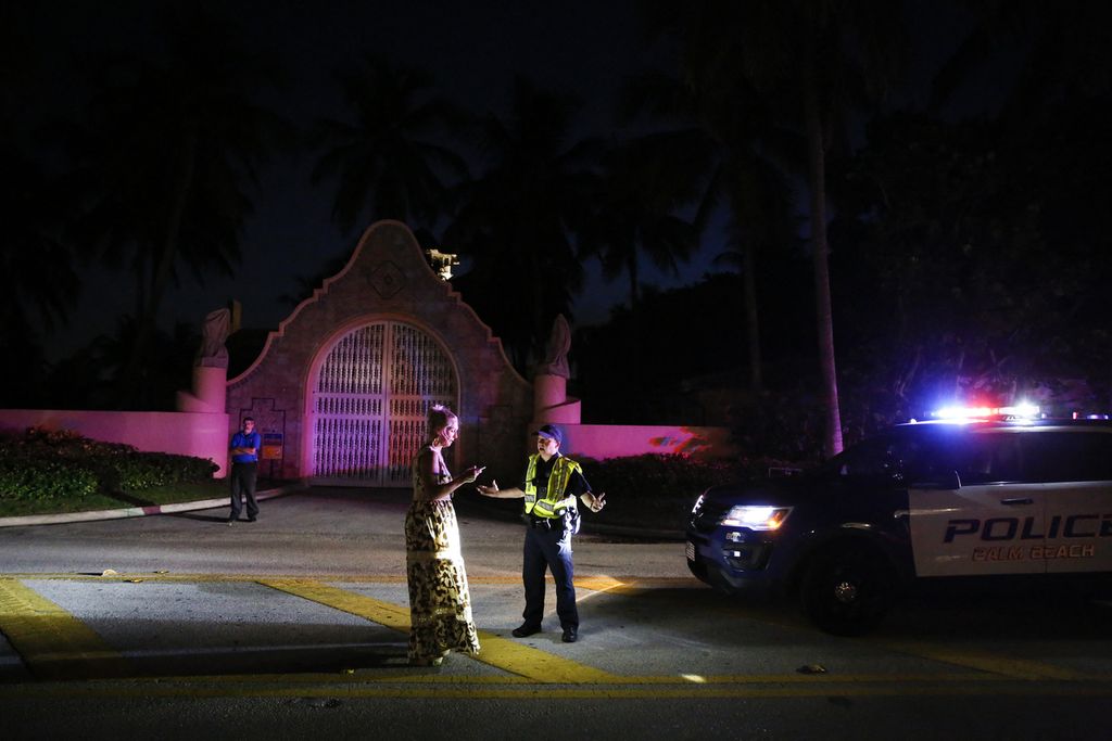 Seorang polisi (kanan) tengah berbicara di depan rumah peristirahatan milik mantan Presiden AS Donald Trump di Mar-a-Lago, Palm Beach, Florida, Amerika Serikat, Selasa (9/8/2022). Properti milik Trump ini digeledah aparat Departemen Kehakiman dan Biro Investigasi Federal AS (FBI), Senin (8/8/2022). 