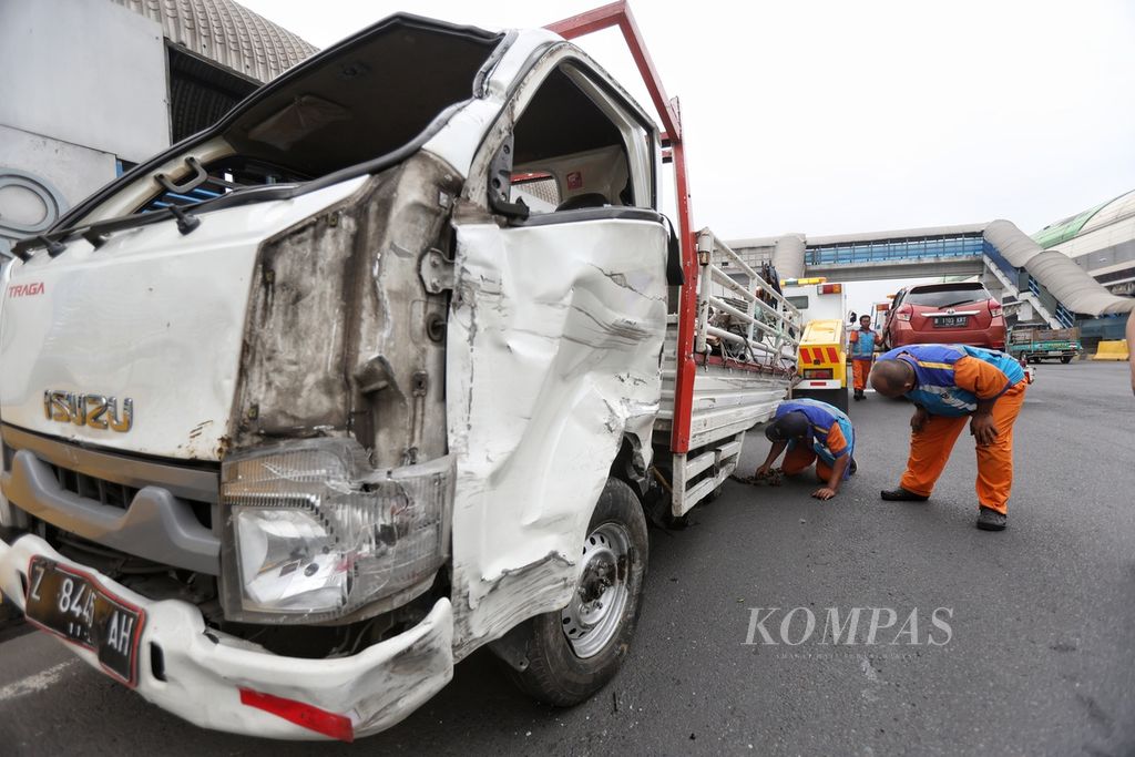 Petugas Jasa Marga memeriksa mobil yang akan diangkut setelah mengalami kecelakaan di Gerbang Tol Halim Utama, Jakarta, Rabu (27/3/2024). Terjadi kecelakaan beruntun tujuh kendaraan di Gerbang Tol Halim Utama. Kecelakaan terjadi akibat supir truk yang diduga mengendarai secara ugal-ugalan. 