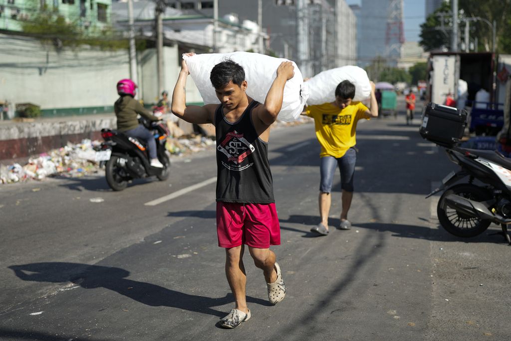 Buruh pengangkut es mengantar pesanan di Quezon, Filipina, Rabu (24/4/2024).