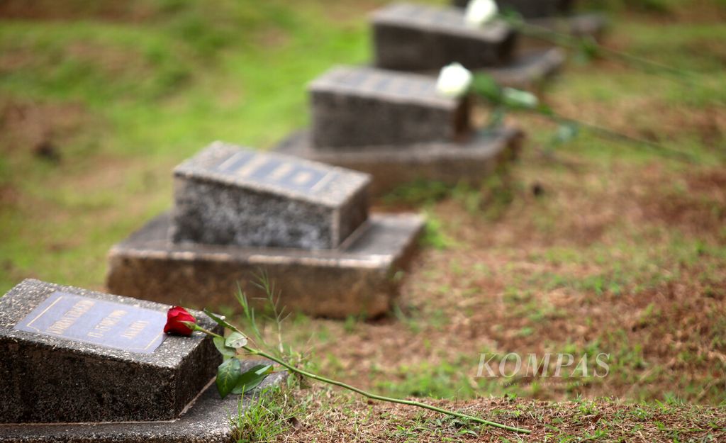 Bunga-bunga diletakkan di atas nisan tempat pemakaman massal korban tragedi Mei pada acara Napak Tilas 24 Tahun Perkosaan Mei 98 di TPU Pondok Ranggon, Jakarta, Selasa (24/5/2022).  