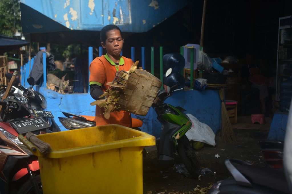 Seorang petugas kebersihan membuang sampah sisa makanan ke tempat sampah di Pasar Palmerah, Kelurahan Gelora, Kecamatan Palmerah, Jakarta Pusat, Senin (3/10/2022). 