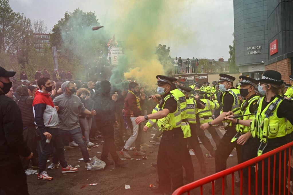 Polisi Inggris berhadapan dengan suporter saat terjadi kekacauan di luar Stadion Old Trafford, Manchester, jelang laga Liga Inggris antara MU lawan Liverpool pada 2 Mei 2021. Kerusuhan terjadi akibat kekecewaan suporter atas keputusan pemilik MU untuk bergabung dengan ide Liga Super Eropa. 