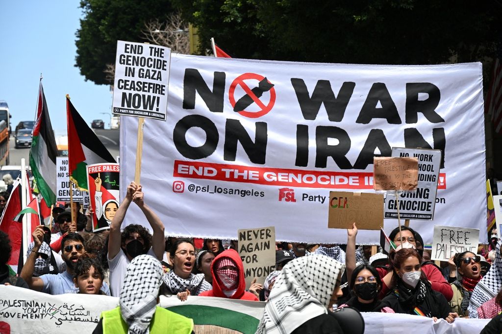 Demonstran membentangkan spanduk bertuliskan ”Tidak Ada Perang terhadap Iran” saat menggelar aksi yang menyerukan gencatan senjata permanen dalam konflik Israel-Hamas di Los Angeles, California, Amerika Serikat, Senin (15/4/2024). 