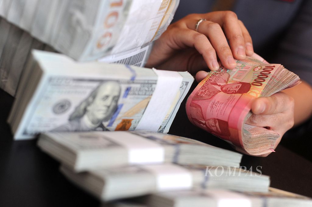 Petugas menghitung mata uang dollar Amerika Serikat dan rupiah di kantor Bank CIMB Niaga, Jakarta, Senin (30/6). 