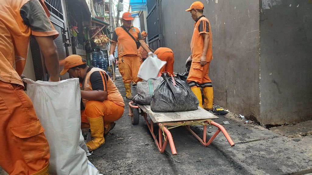 Petugas gabungan tengah membersihkan sampah-sampah sisa kebakaran di Kelurahan Kalianyar, Kecamatan Tambora, Jakarta Barat, Senin (2/1/2023).