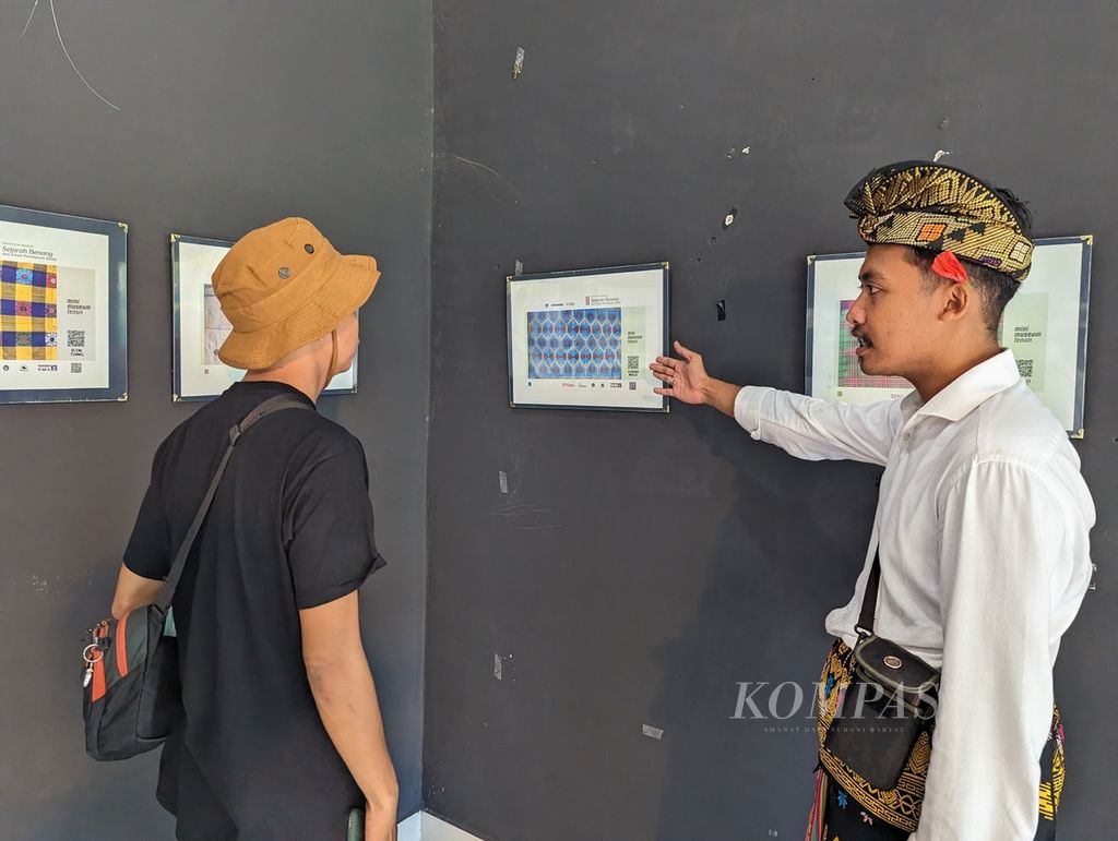 Rozi Wirawan Zuhdi (23) menjelaskan tentang kain tenun dan cara mendapatkan informasi lebih lengkap kepada pengunjung Mini Museum Tenun Sasak di Taman Budaya NTB, Mataram, Sabtu (24/12/2022) lalu. Mini museum tersebut merupakan upaya untuk membuat masyarakat lebih mengetahui nilai dan makna tenun lebih mendalam.