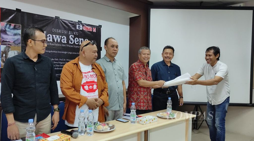 Perupa I Wayan Sujana Suklu (kanan) menyerahkan kenang-kenangan kepada akademisi dan kritikus sastra I Nyoman Darma Putra (ketiga dari kanan) dalam diskusi membedah buku berjudul <i>Nawa Sena </i>di Kantor Perwakilan <i>Kompas </i>Bali di Denpasar, Jumat (23/6/2023). Buku <i>Nawa Sena</i> adalah karya kolaborasi perupa I Wayan Sujana Suklu dan sastrawan Anak Agung Sagung Mas Ruscitadewi, yang diterbitkan Bali Mangsi Foundation.