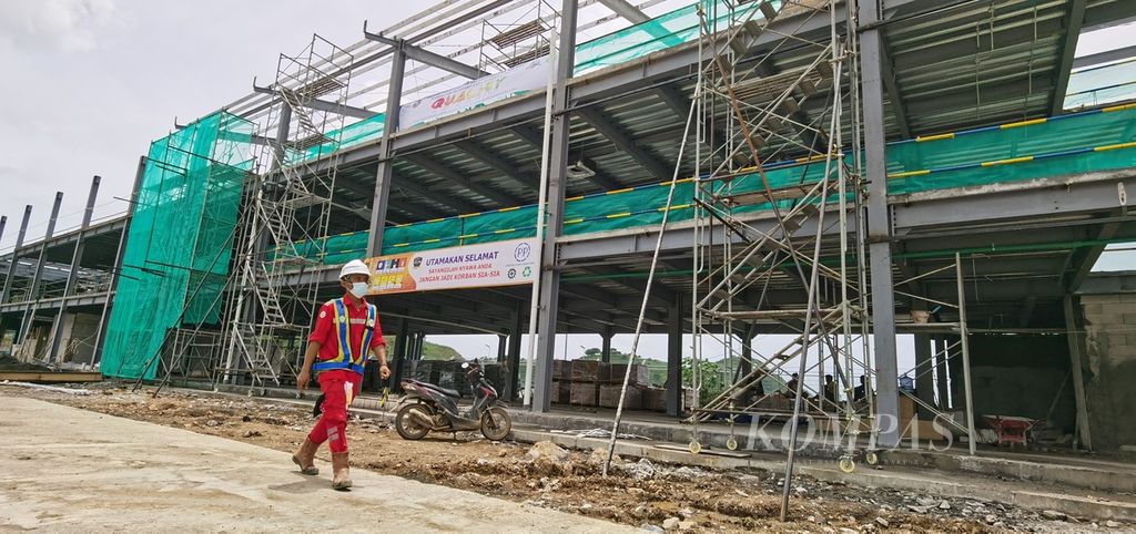 Pekerja melintas di depan gedung VIP Village Sirkuit Internasional Jalan Raya Pertamina Mandalika di Kuta, Pujut, Lombok Tengah, Nusa Tenggara Barat, Jumat (28/1/2022). Saat ini, berbagai persiapan dikebut jelang penyelenggaraan MotoGP yang akan berlangsung pada 18-20 Maret 2022 mendatang.