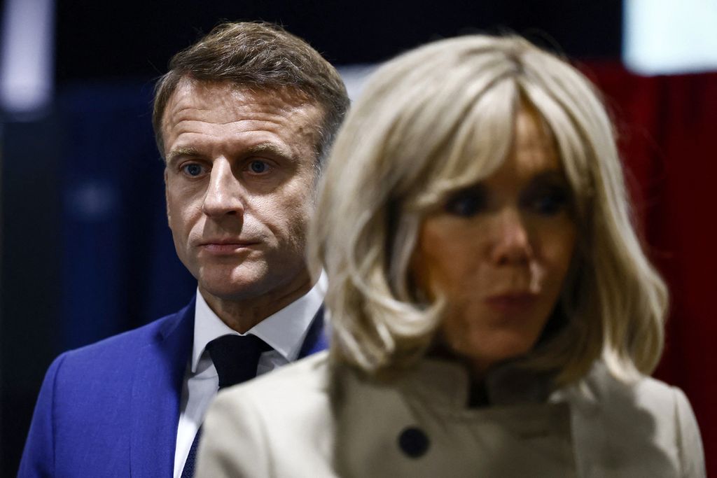 Presiden Perancis Emmanuel Macron dan istrinya, Brigitte Macron, berdiri di sebuah tempat pemungutan suara sebelum menggunakan hak pilihnya di Le Touquet-Paris-Plage, Perancis utara, Minggu (30/6/2024). 