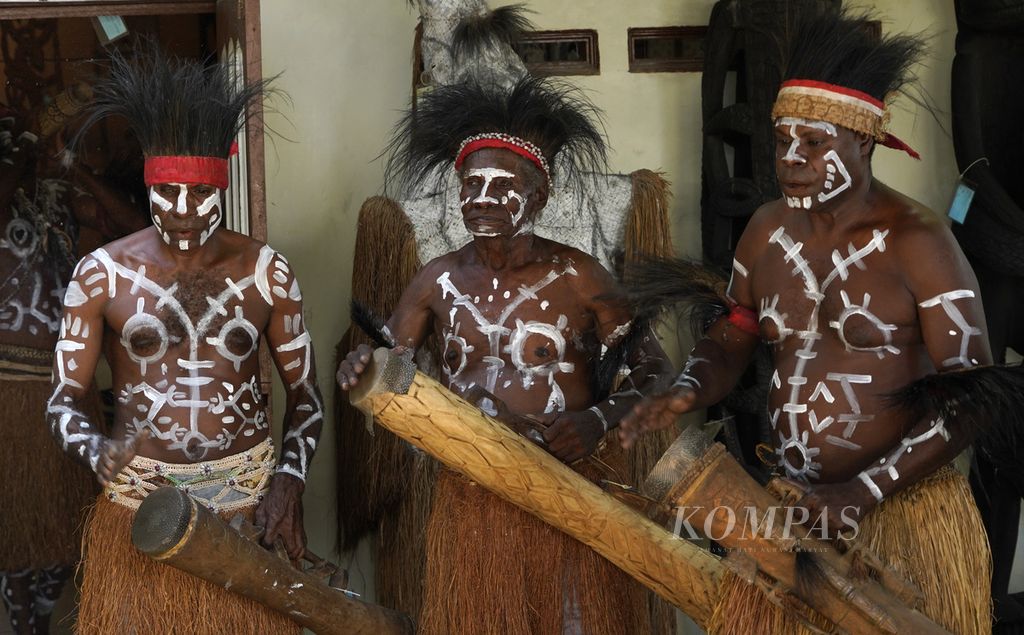 Warga Suku Kamoro yang tergabung dalam Yayasan Maramowe memukul tifa saat mengiringi tarian untuk menyambut tamu yang datang ke sekretariat, bengkel kerja, dan ruang pamer ukiran mereka di Kampung Nawaripi, Distrik Wania, Kabupaten Mimika, Jumat (18/3/2022).  