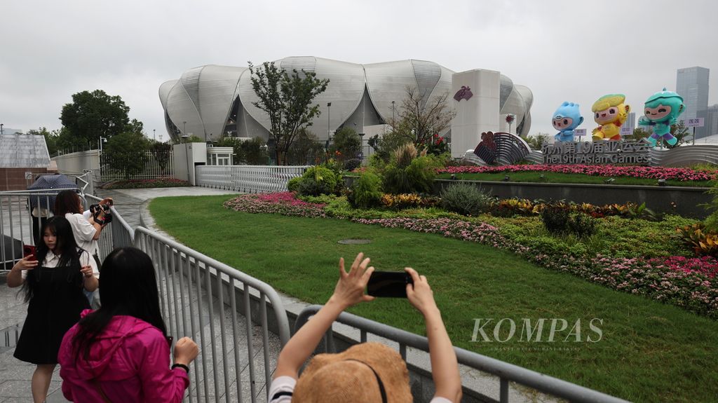 Warga berfoto-foto di luar Hangzhou Olympic Sports Centre Stadium yang menjadi lokasi pembukaan Asian Games 2022 di Kota Hangzhou, Provinsi Zhejiang, China, Kamis (21/9/2023). Stadion ini dijuluki The Big Lotus karena desain arsitekturnya menyerupai bunga teratai raksasa.