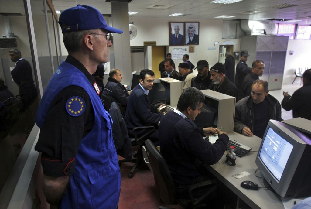 Seorang petugas pengawas dari Uni Eropa memantau petugas perbatasan Palestina memeriksa dokumen warga yang hendak melintas di pos perlintasan Rafah, yang menghubungkan Palestina dan Mesir, 9 Maret 2007. 
