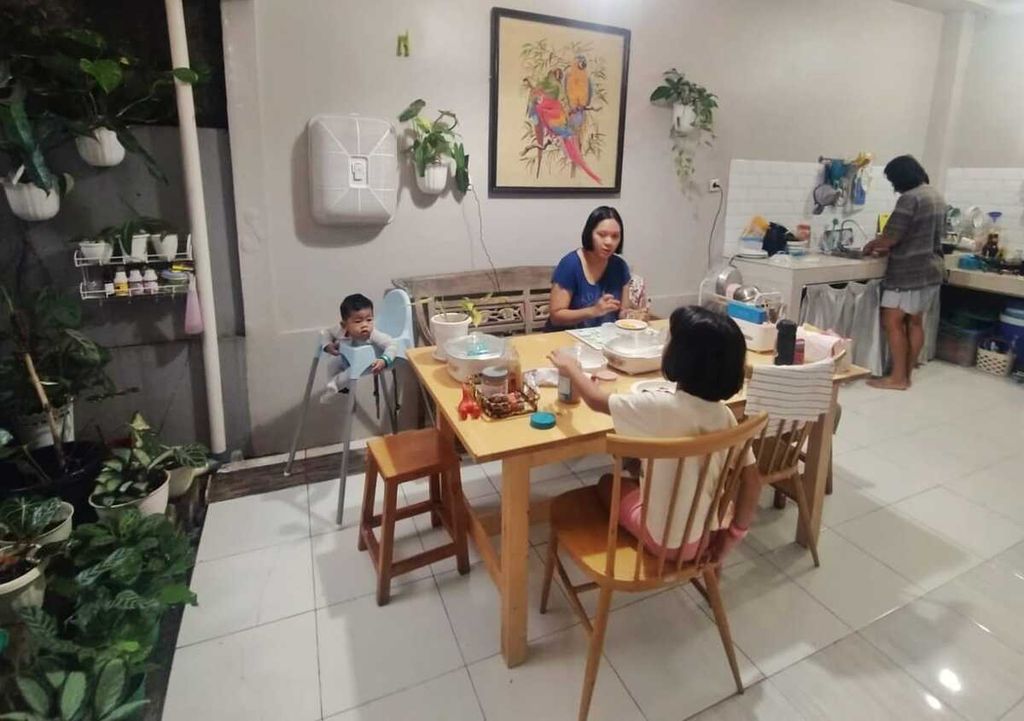 Keluarga kecil Imanina Aditiawati menikmati makan malam di ruang makan yang dibuat terbuka dan bersanding dengan taman kecil berisi koleksi tanaman sang ibu.